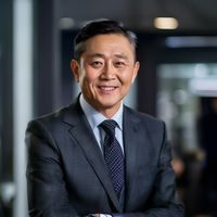 番号大全创始人陈明远，穿着深色西装，面带自信微笑，在上海办公室内接受采访时的专业形象
